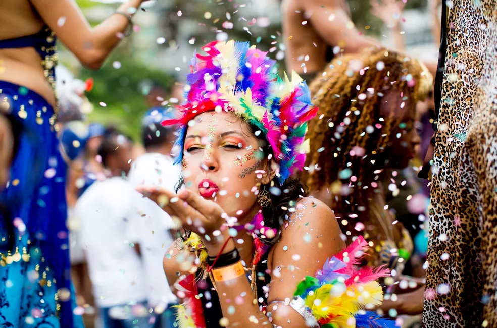 Menina soprando confetes no bloco de rua no carnaval 2024 - veja as datas dos blocos na Zona Sul