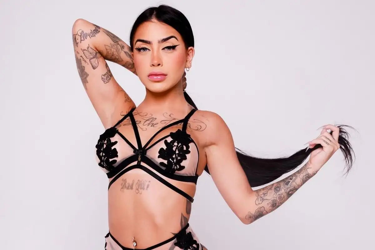 MC Mirella em ensaio de estúdio, de lingerie preta, com tatuagens nos braços